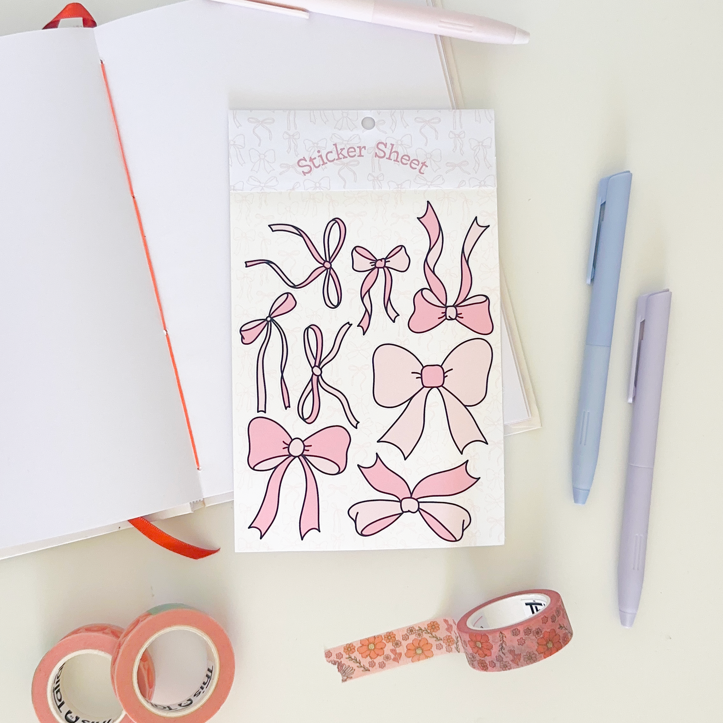 Sticker sheet with pink bowls. background: notebook, pens and washi tapes