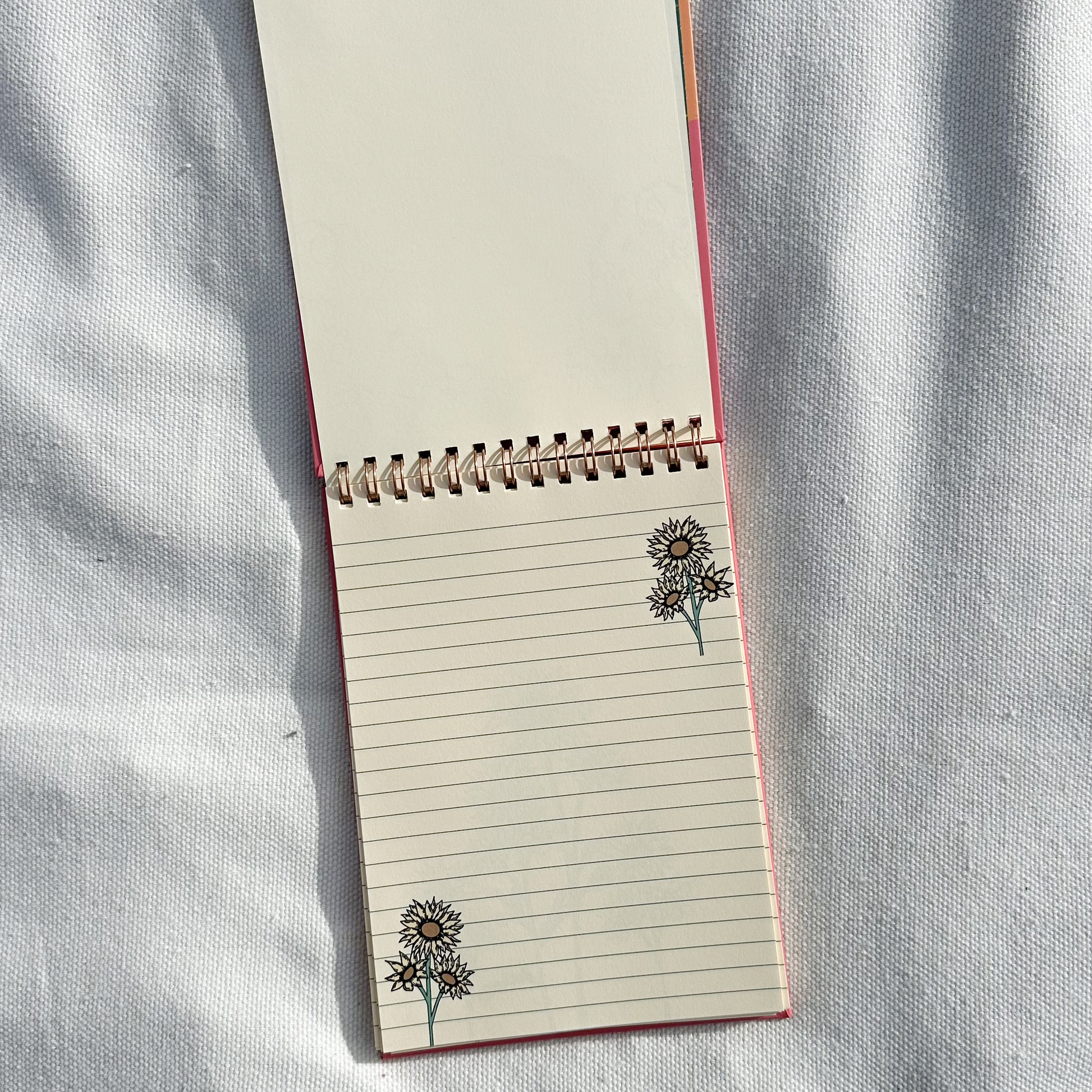 Spring notepad showing flower design in a light beige towel as background