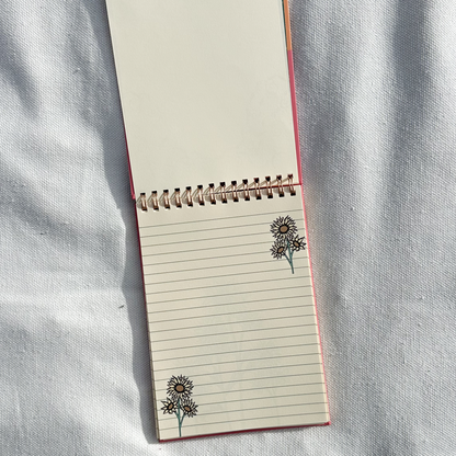 Spring notepad showing flower design in a light beige towel as background
