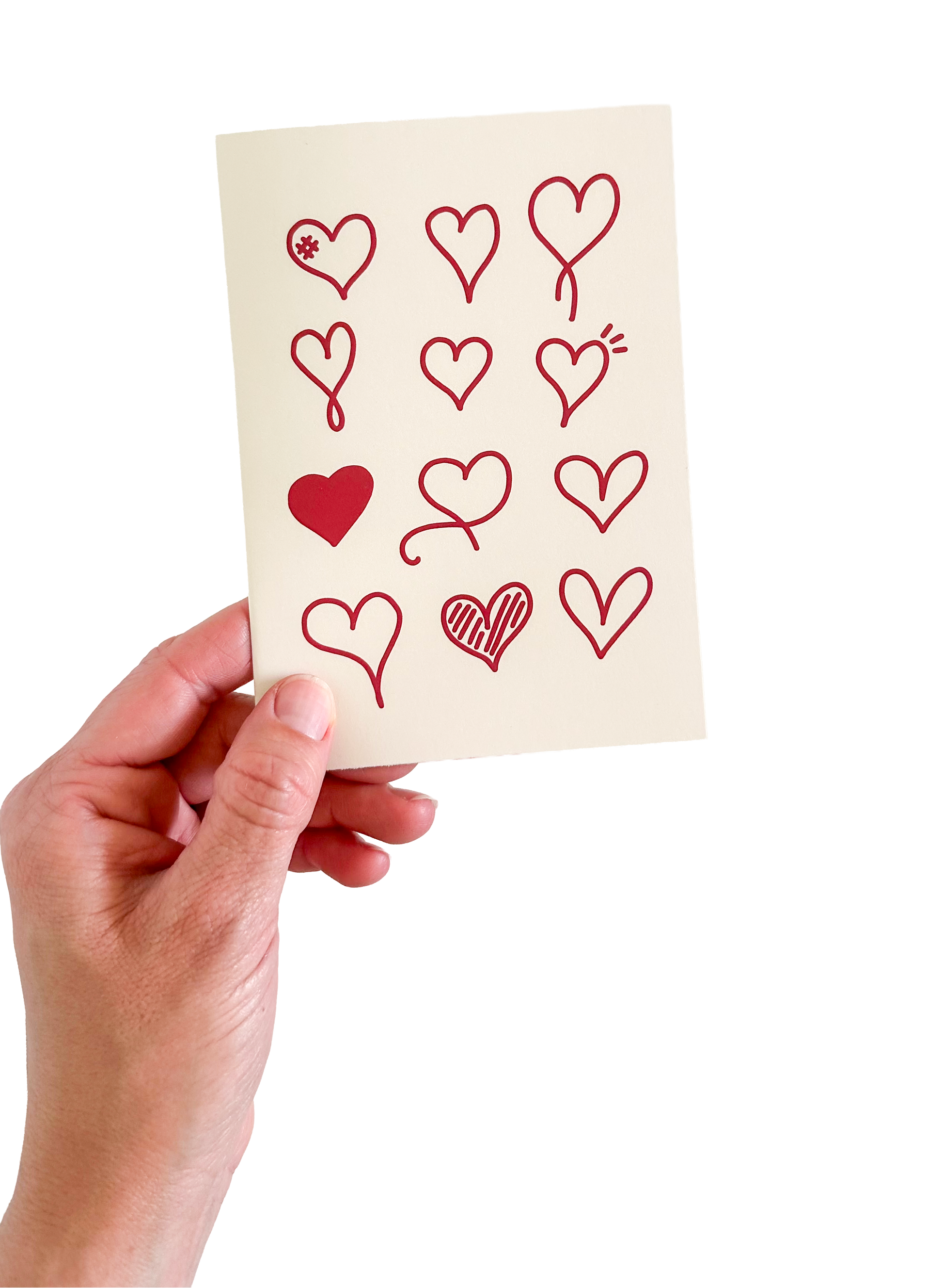 Hand holding a card with red heart designs on a white background