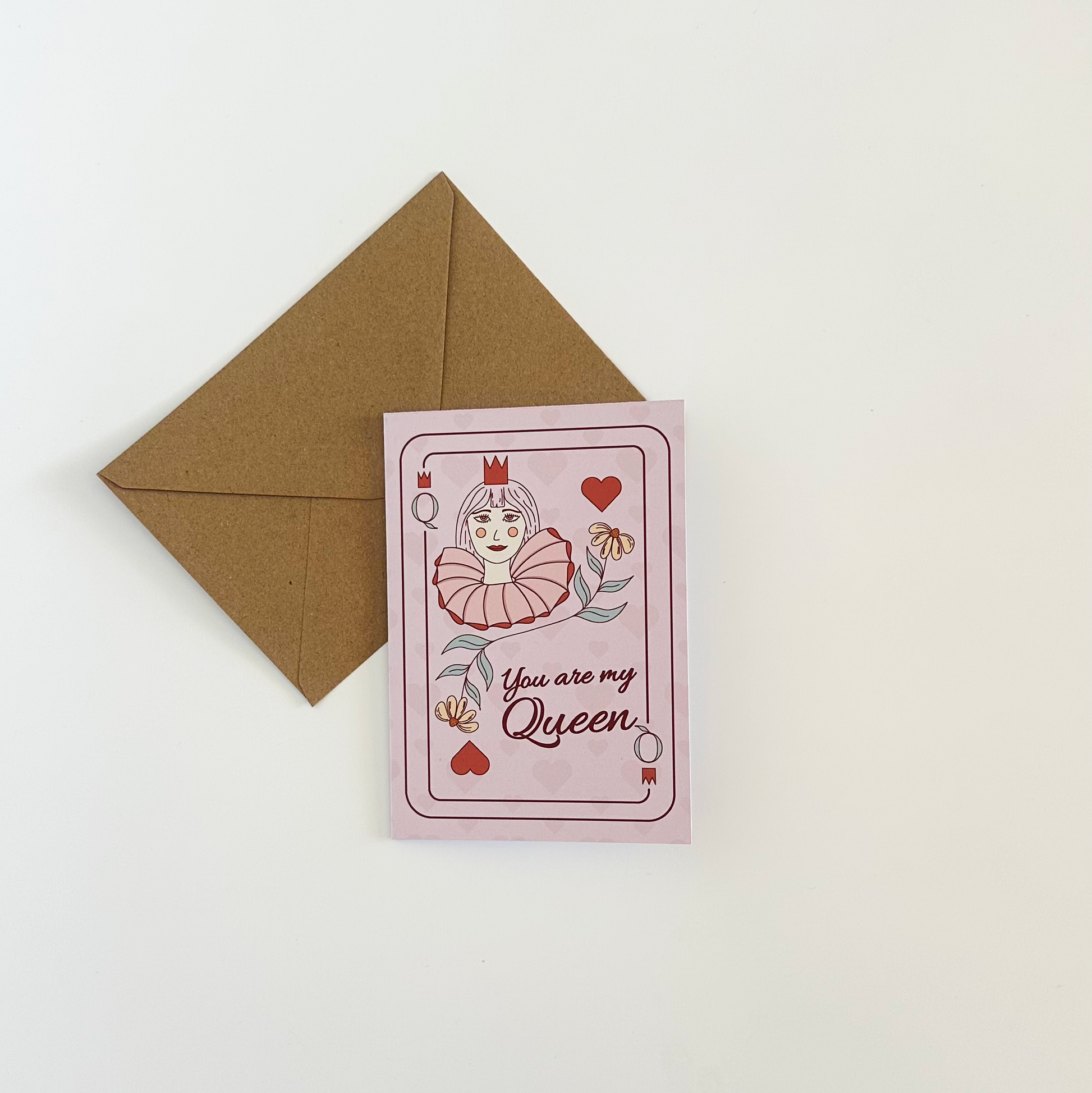 Greeting Card with 'You are my Queen' text and a decorative design referring to queen of harts, accompanied by a brown envelope on a white background.