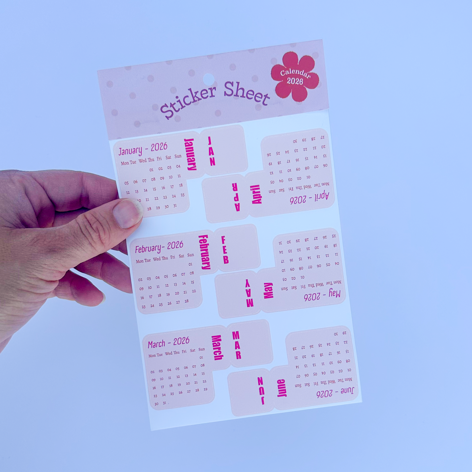 Hand holding a sticker sheet with pink and white design on a white background