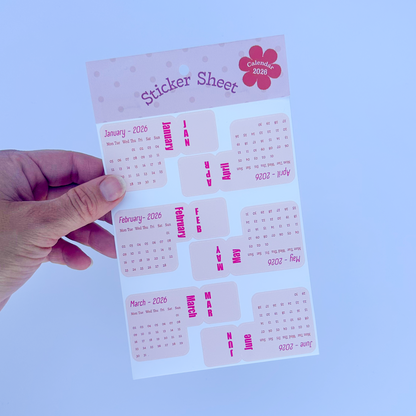 Hand holding a sticker sheet with pink and white design on a white background