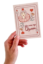 Hand holding a card with a queen of hearts illustration and text 'You are my queen' on a white background